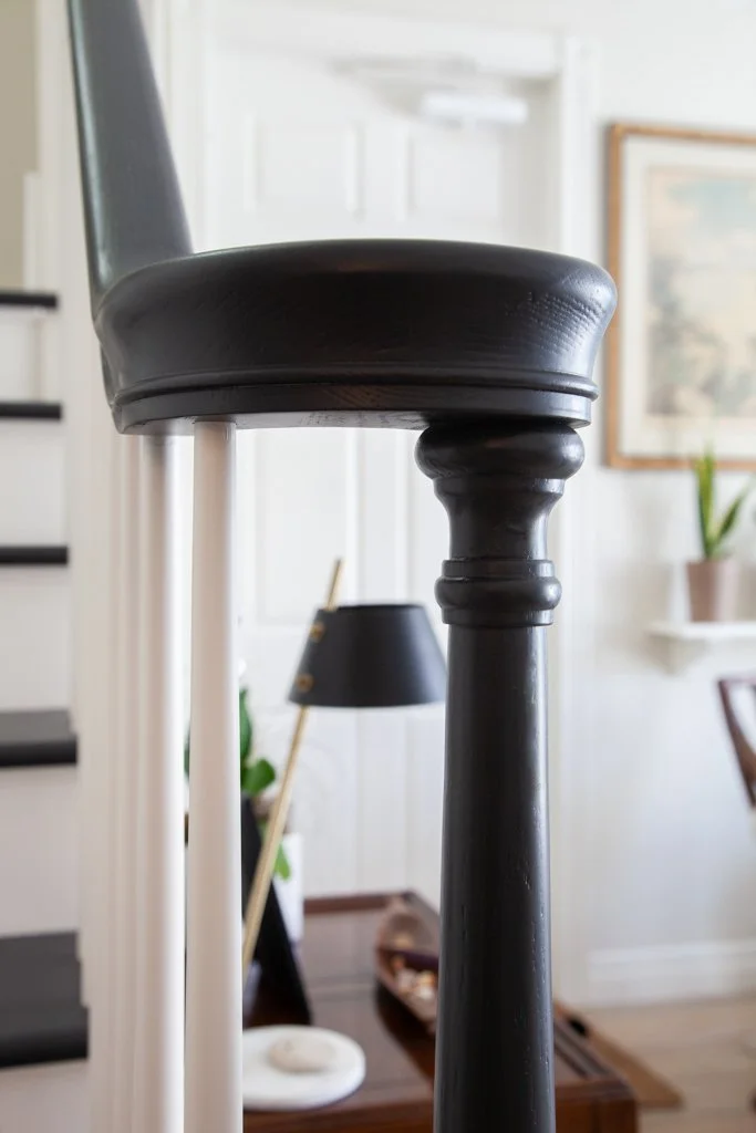 Close-up of two chair legs, one black and one white, with a blurred background of a living room interior.