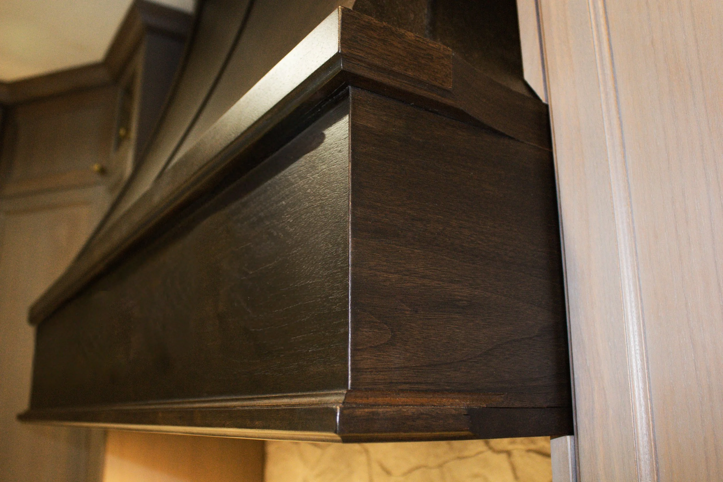Close-up of a dark wooden cabinet with a light-colored countertop in an indoor setting.