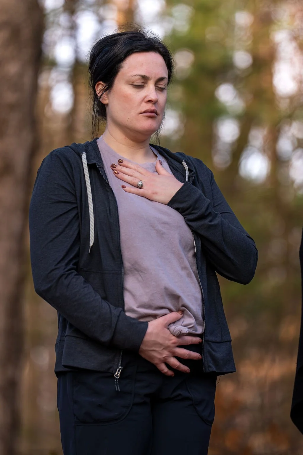 woman stands with a hand on womb and heart connecting to her vision