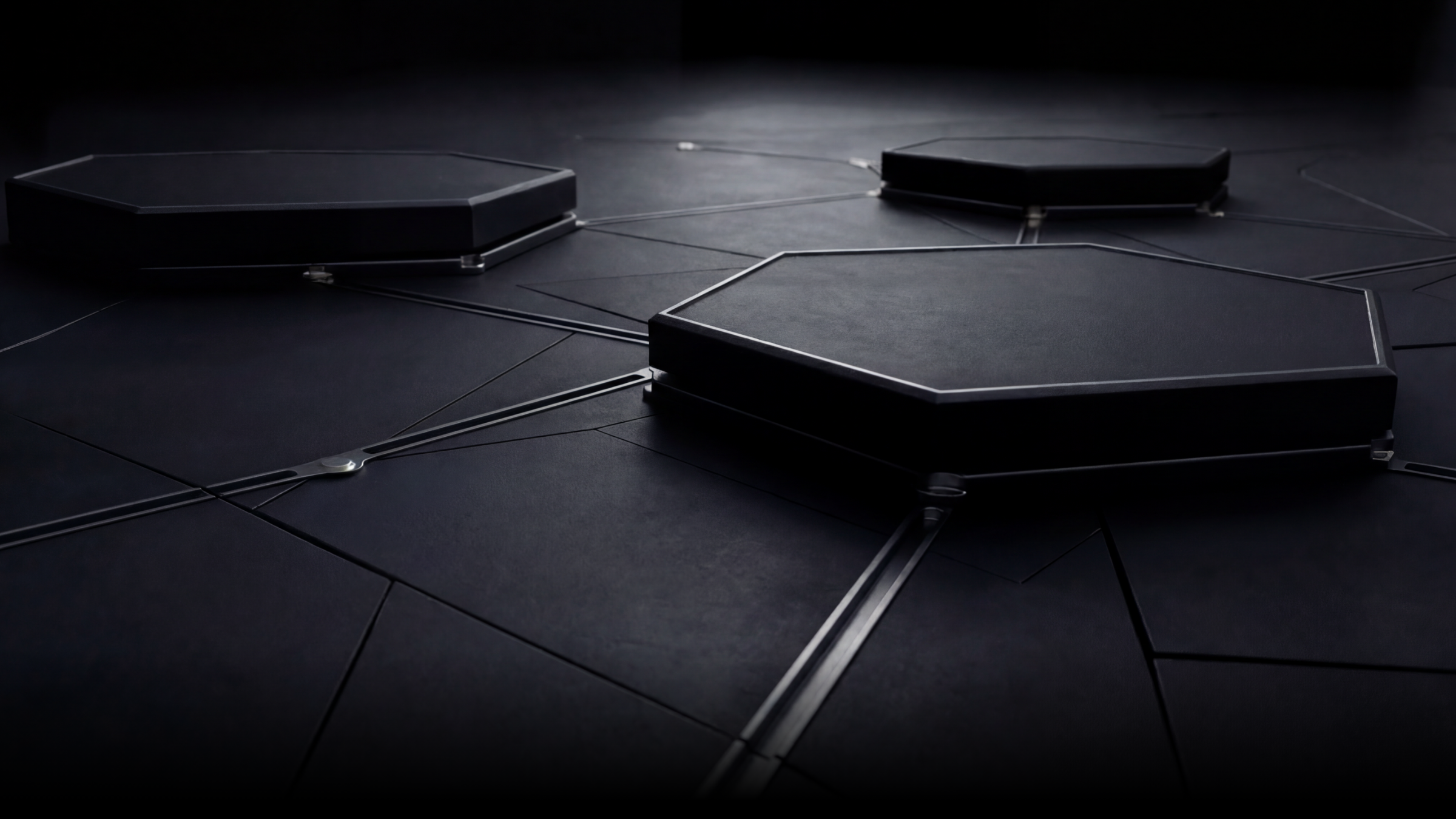 Close-up of a modern, minimalist, black geometric tile floor with interconnected hexagonal tiles and metallic connecting strips.