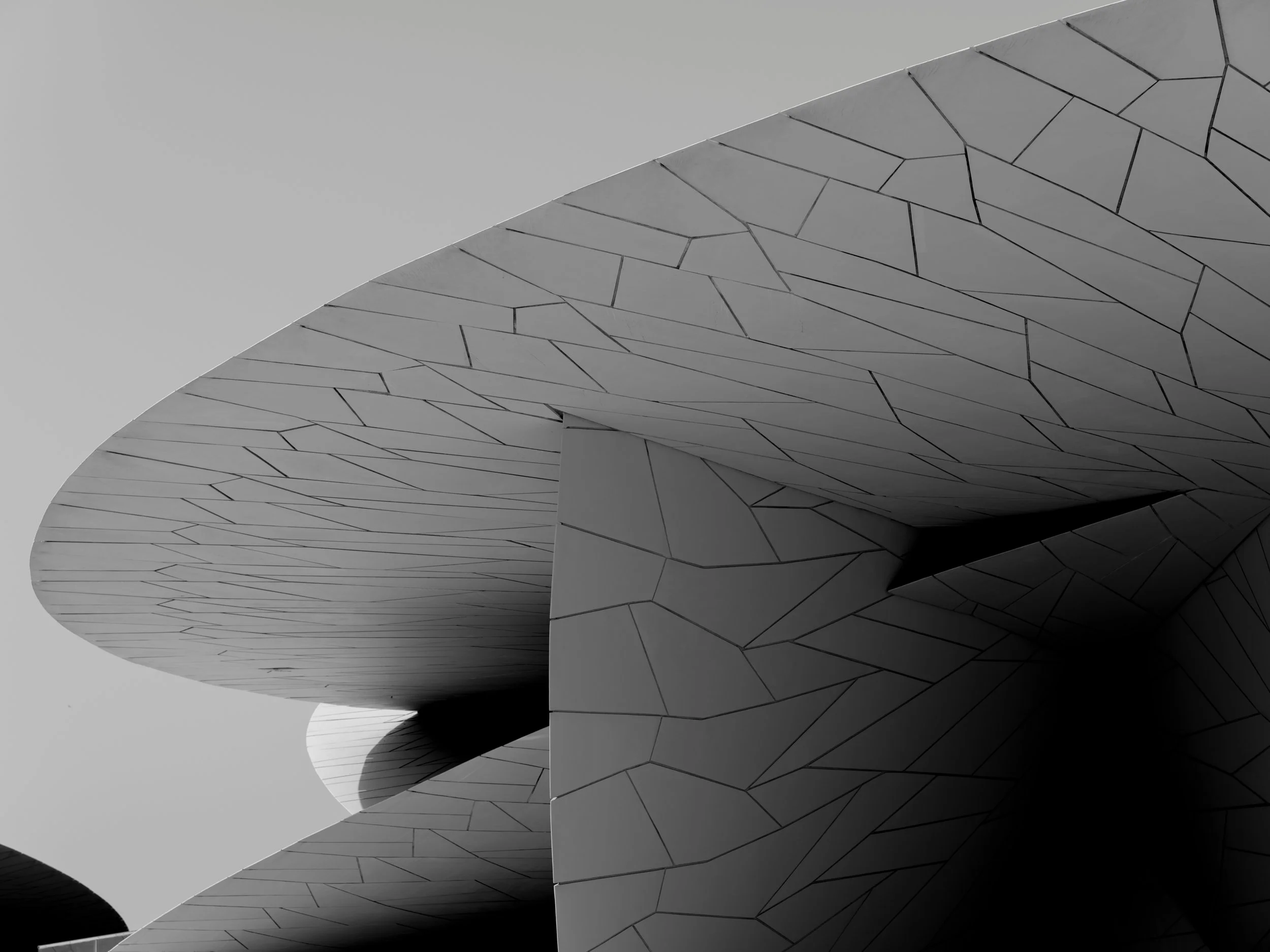 Abstract architectural structure with curved, layered surfaces and geometric patterns in black, white, and gray tones.