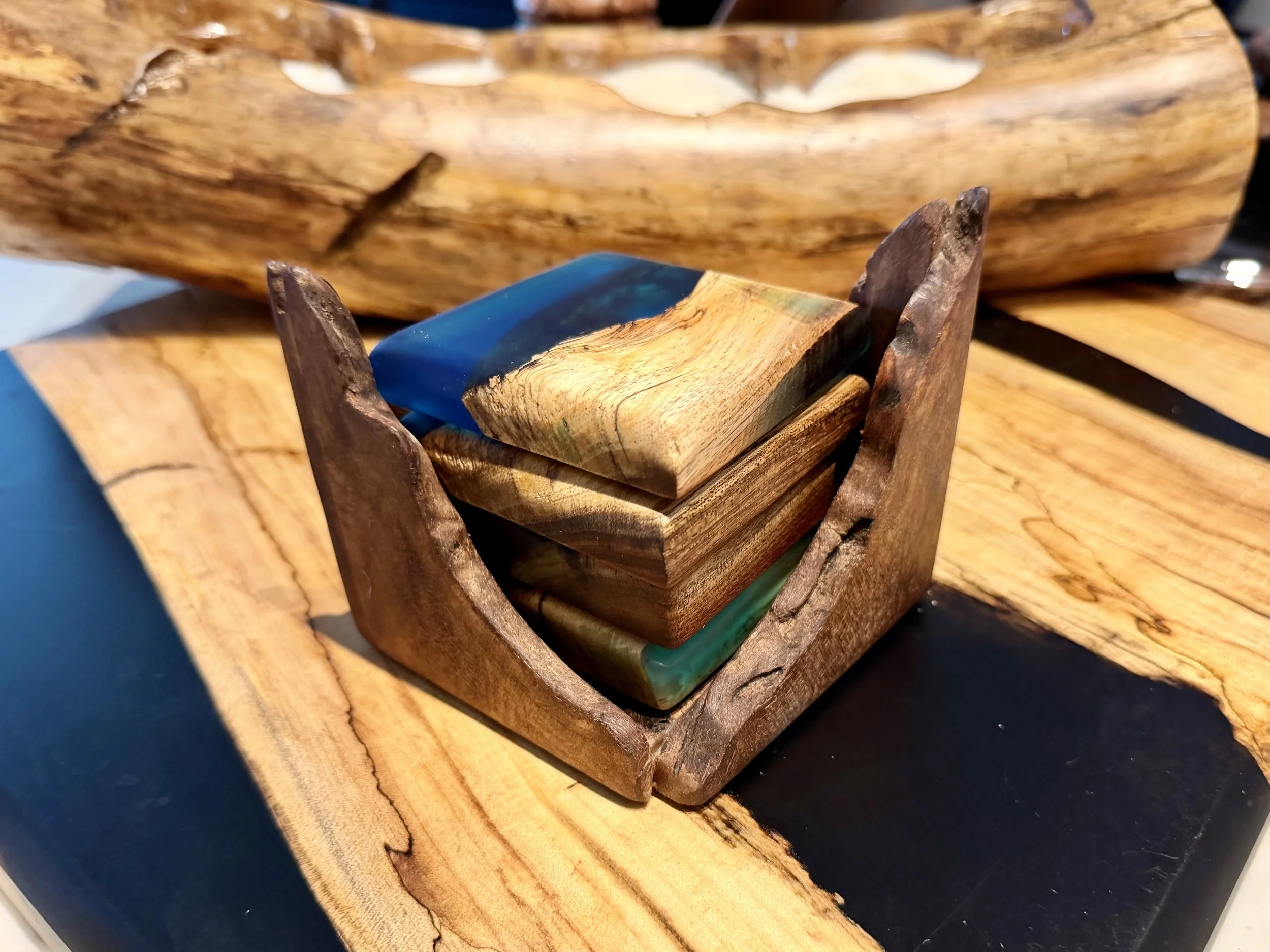 A wooden box containing colorful resin paperweights on a wooden surface.