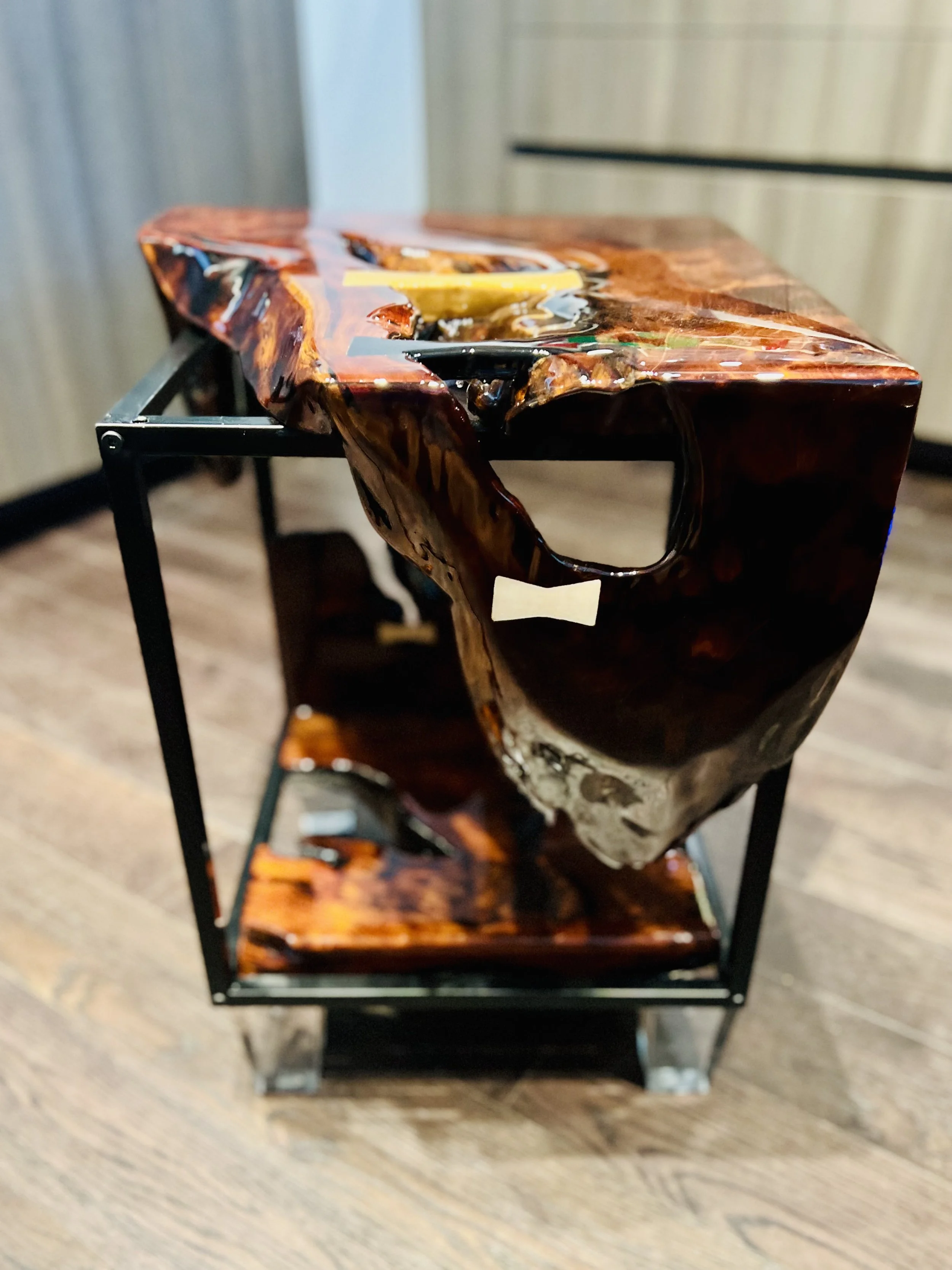 Close-up of a polished, carved redwood burl wood sculpture side table mounted on a black metal stand in an indoor setting.