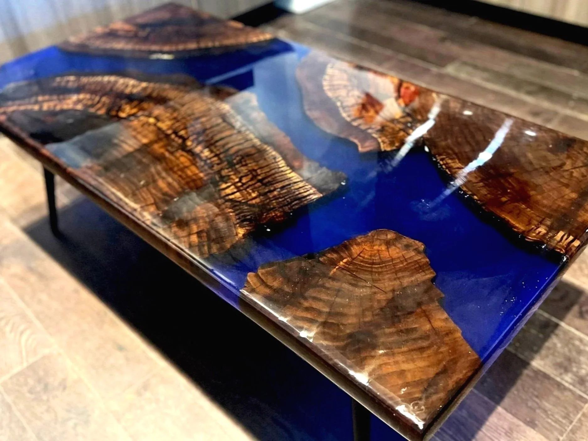 Epoxy resin river table with dark wood segments and blue resin