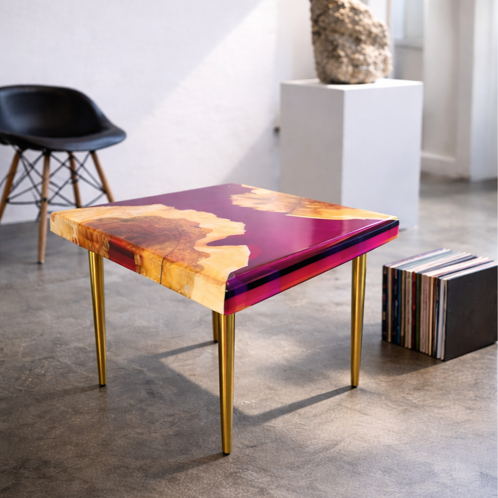 A square table with a colorful, glossy surface and gold legs in a room with a black chair, a sculpture on a white pedestal, and a vinyl record collection on the floor.