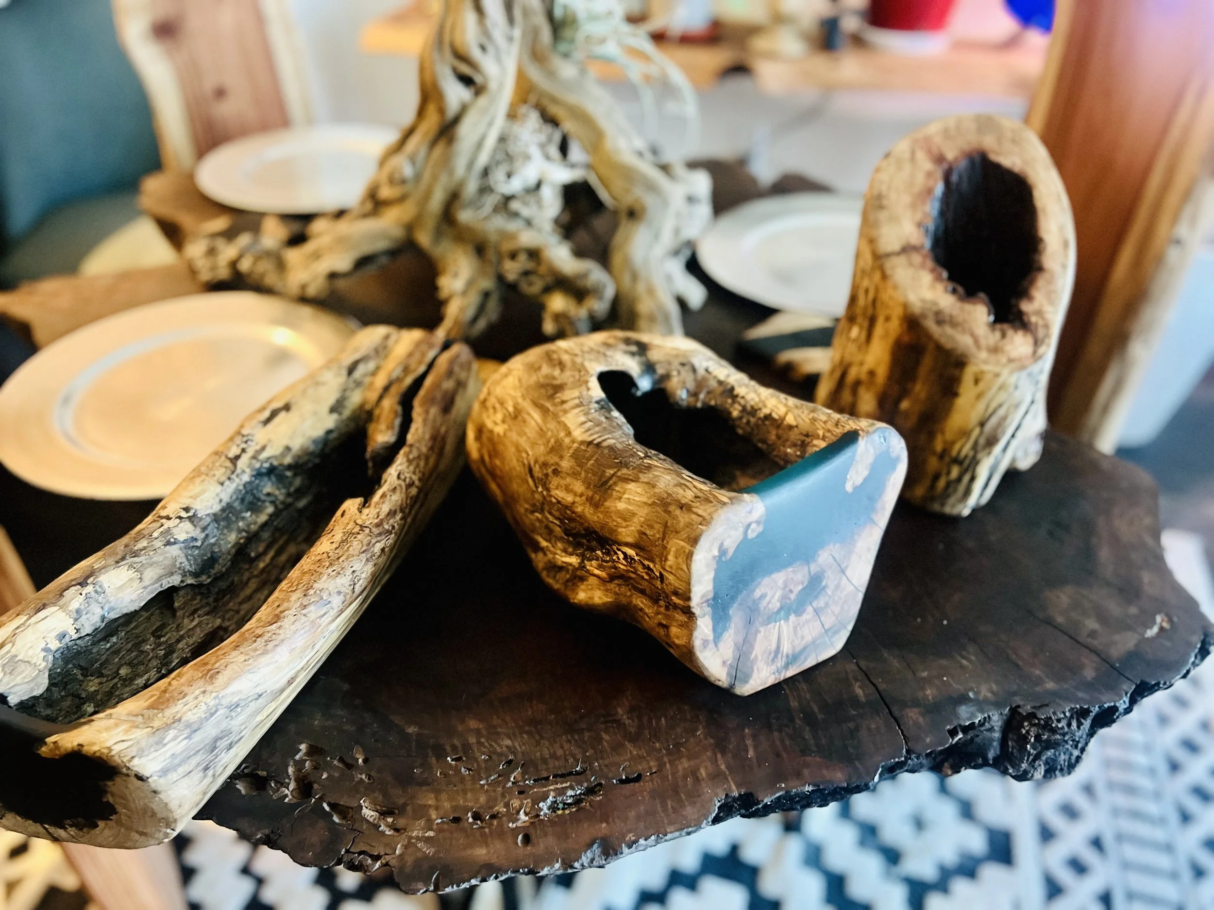 Decorative wooden sculpture resembling hands and natural driftwood pieces arranged on a dark wooden tabletop.