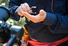 Close-up of a person holding a small object in one palm and examining it with a handheld magnifier.