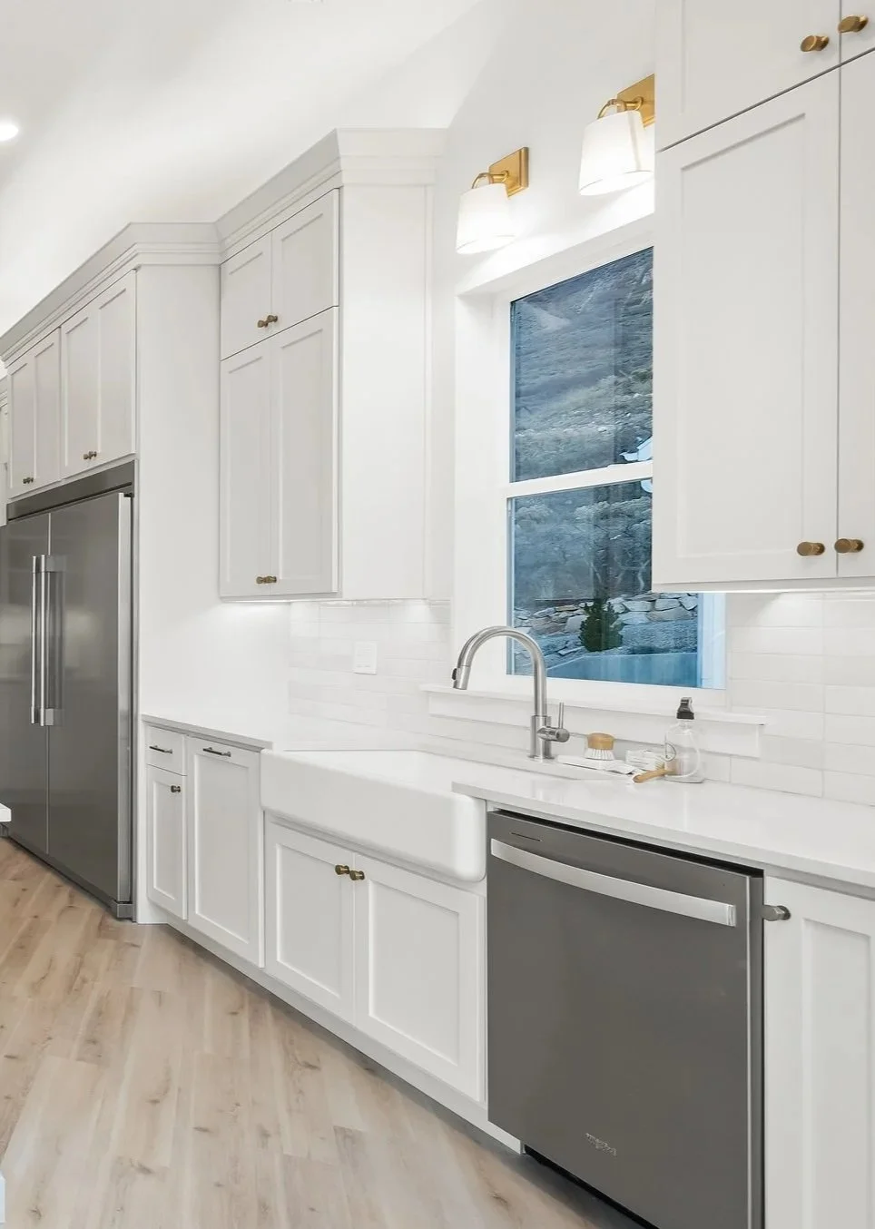 Bright, modern, open-concept kitchen and dining area with large windows, white cabinetry, a light blue kitchen island, and wood flooring.