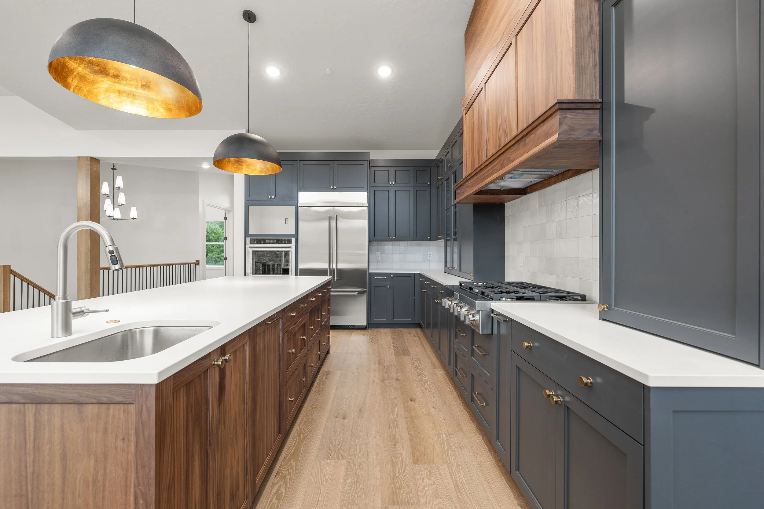 Open-concept kitchen and dining area with large windows, a wooden dining table with six chairs, a kitchen island with three stools, dark gray cabinets, and a sliding glass door leading outside.