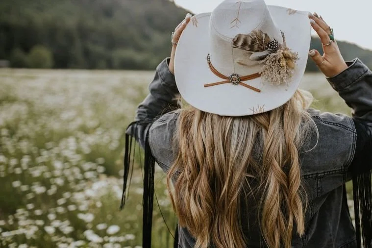 Woman with long dimensional blonde hair wearing a western hat outdoors