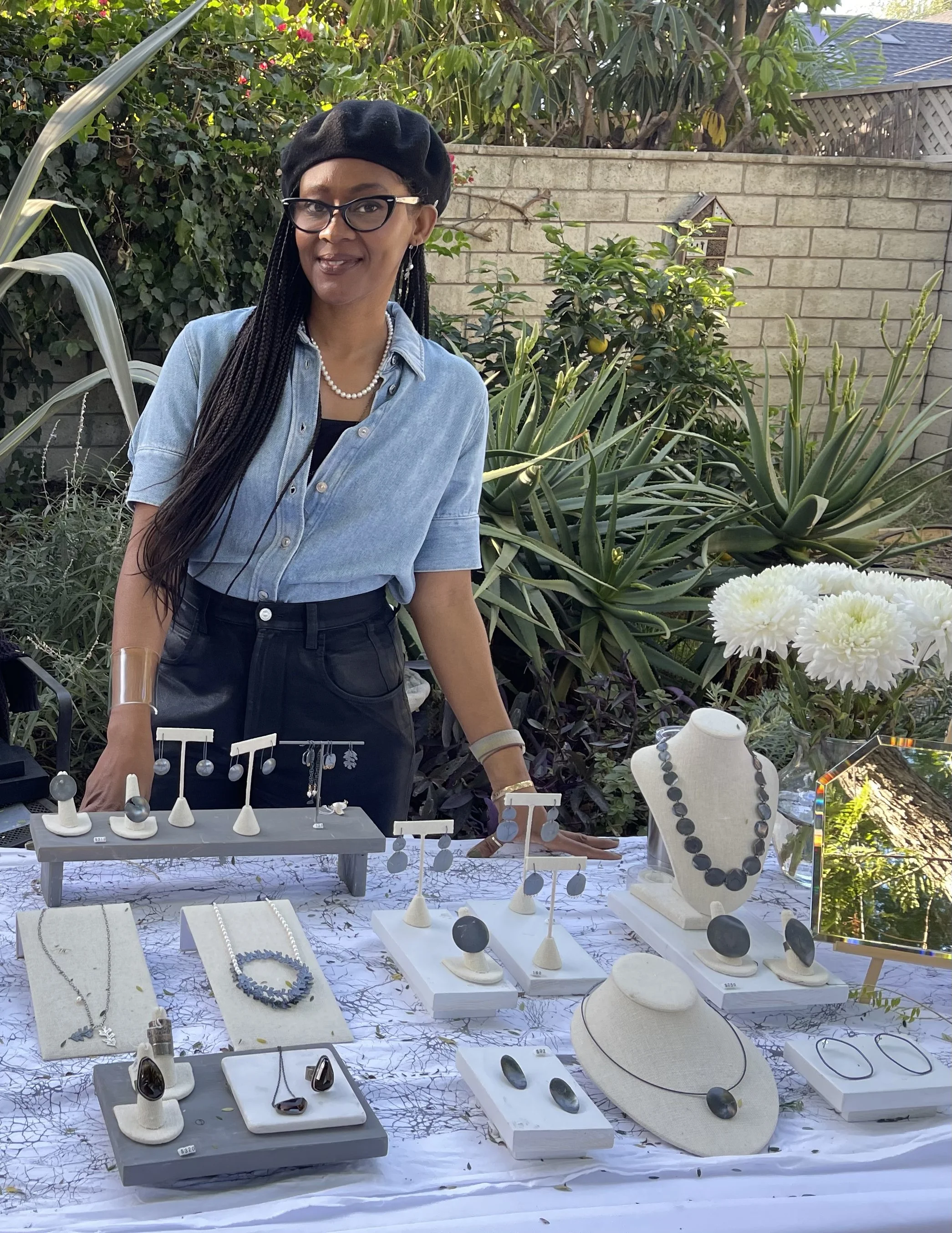 studio jeweler charmaine vegas in front of her table displaying charmaines  handmade jewelry during Jivita Harris backyard studio garden party in Long Beach California