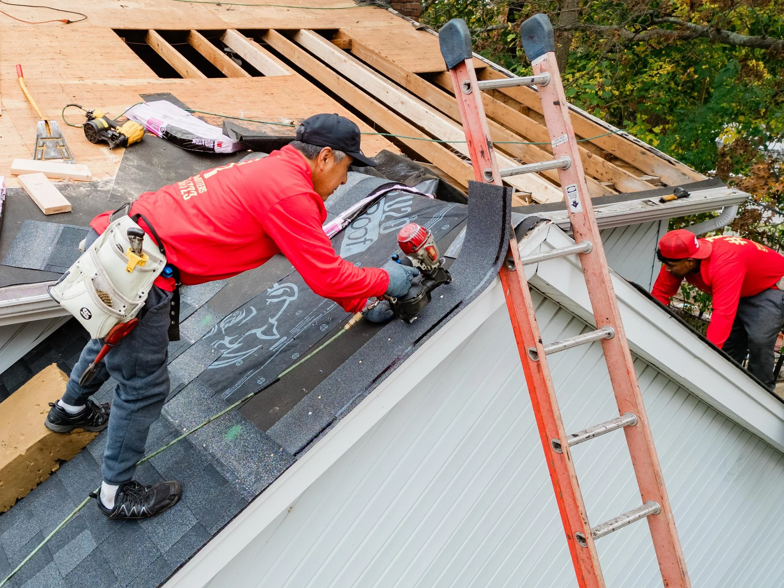 Responsible Remodeling Employees Adding Shingles To Roof With Nail Gun