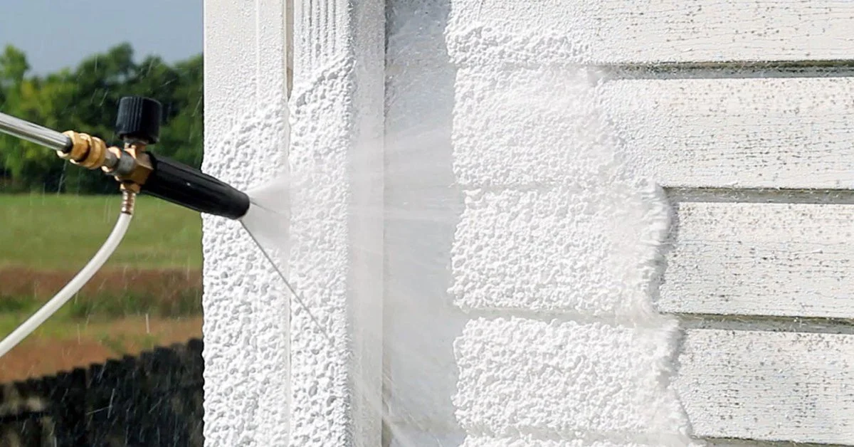 Power washing the exterior wall of a house.