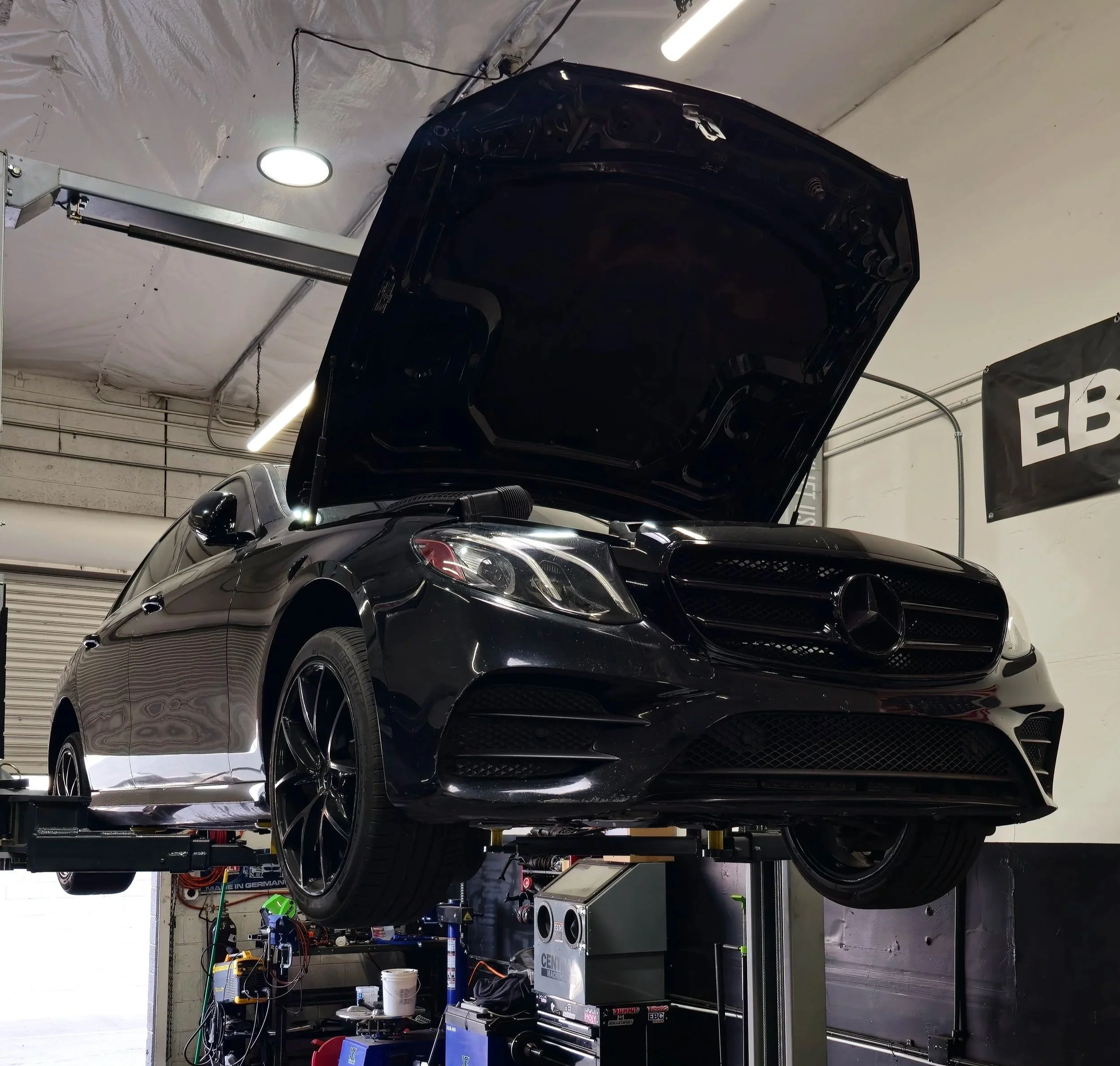 Mercedes-Benz E63 AMG elevated on a lift receiving expert performance service at the Haus of Euro facility in Tempe, AZ