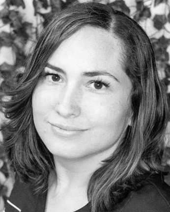 Black and white portrait of a woman with shoulder-length hair, smiling softly, with a leafy background.