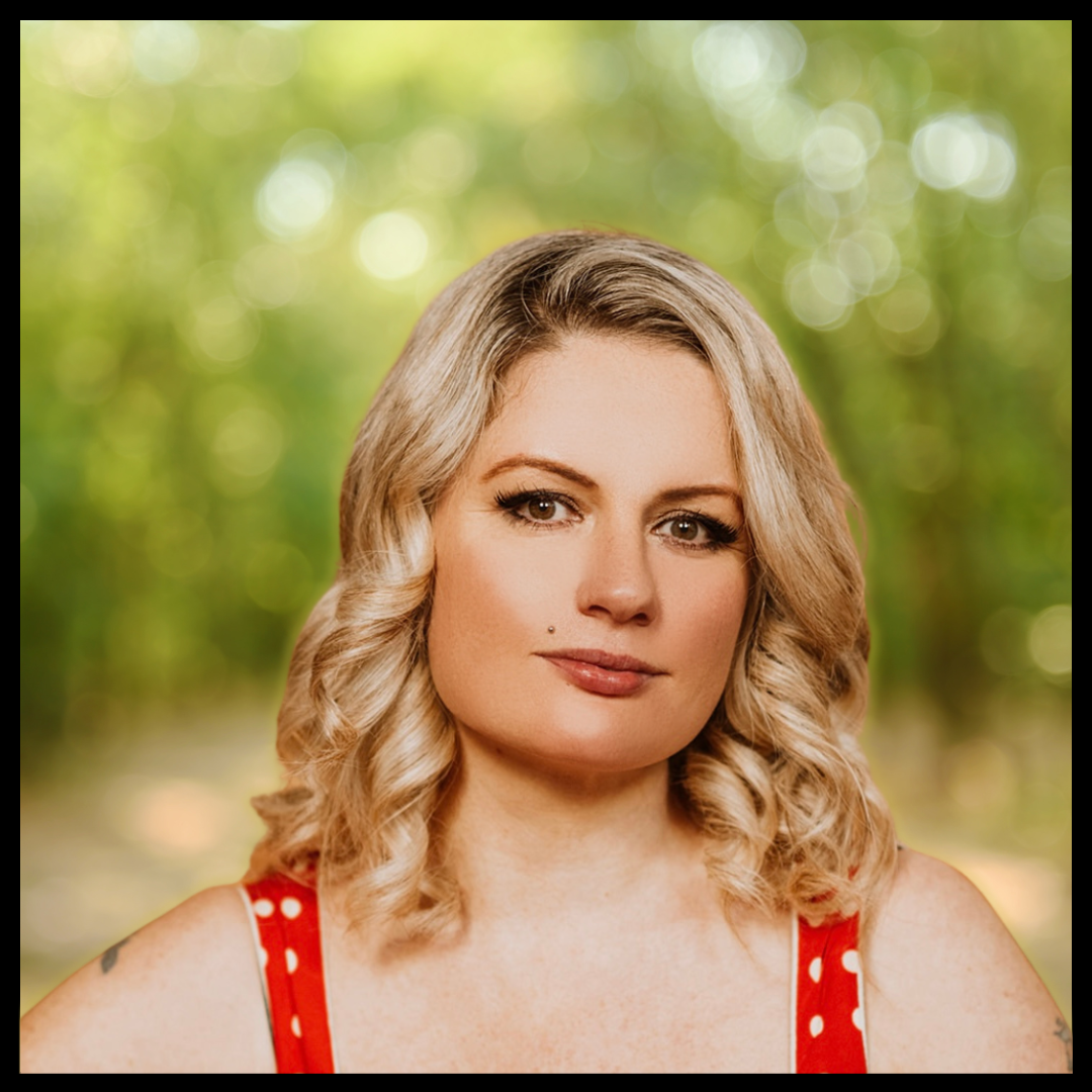 A smiling woman with blonde hair in a polka dot dress, set against a blurred background.