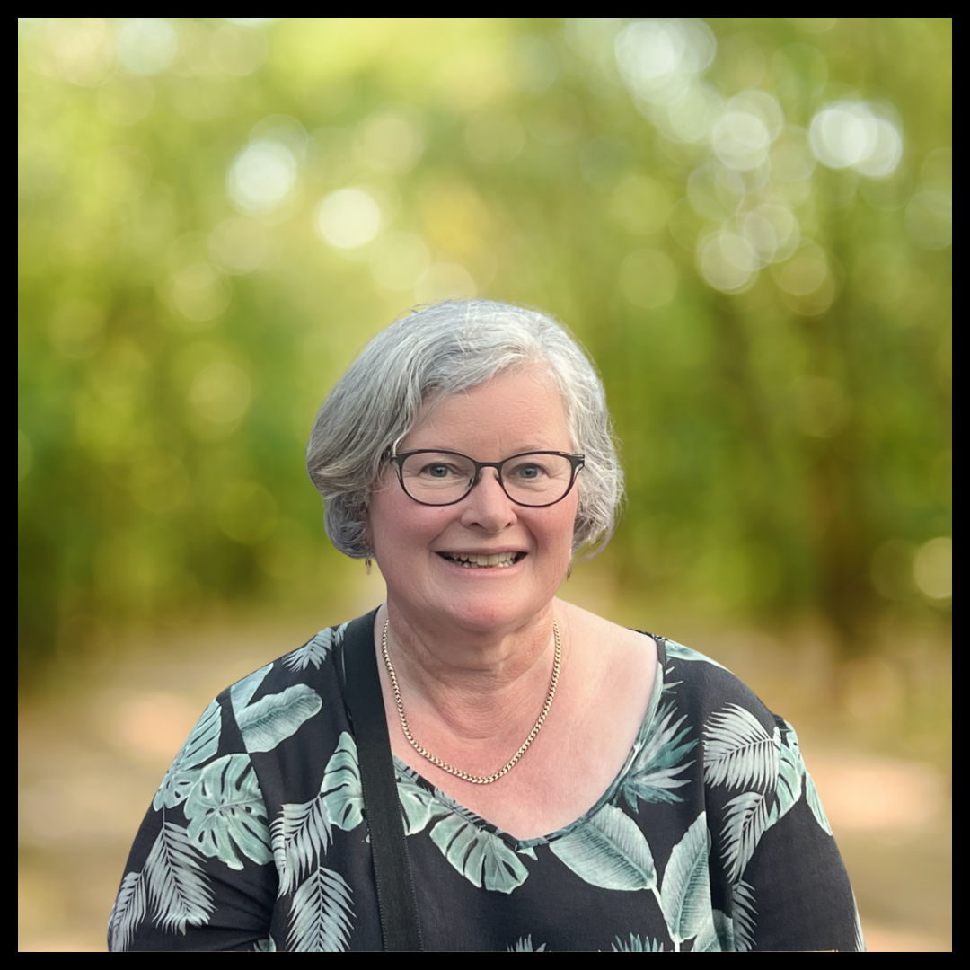 Smiling woman  with short hair, wearing a black shirt with teal coloured patterns on it