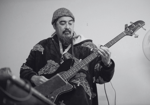 A man wearing a beanie hat playing on an electric guitar