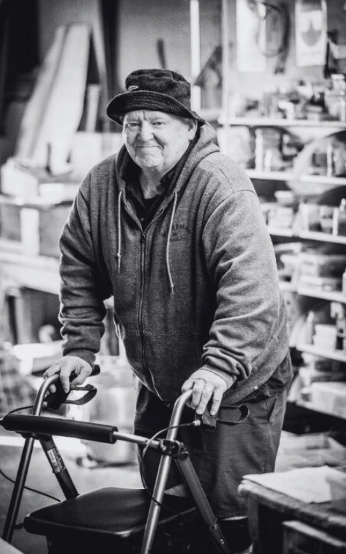 Man wearing bucket hat using walker smiling.