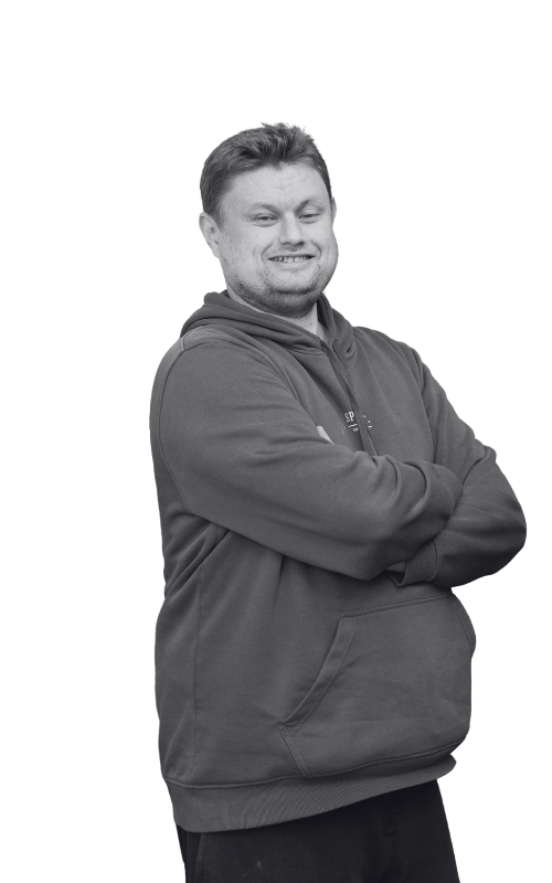 A black and white photo of a smiling man with his arms crossed in front of him.