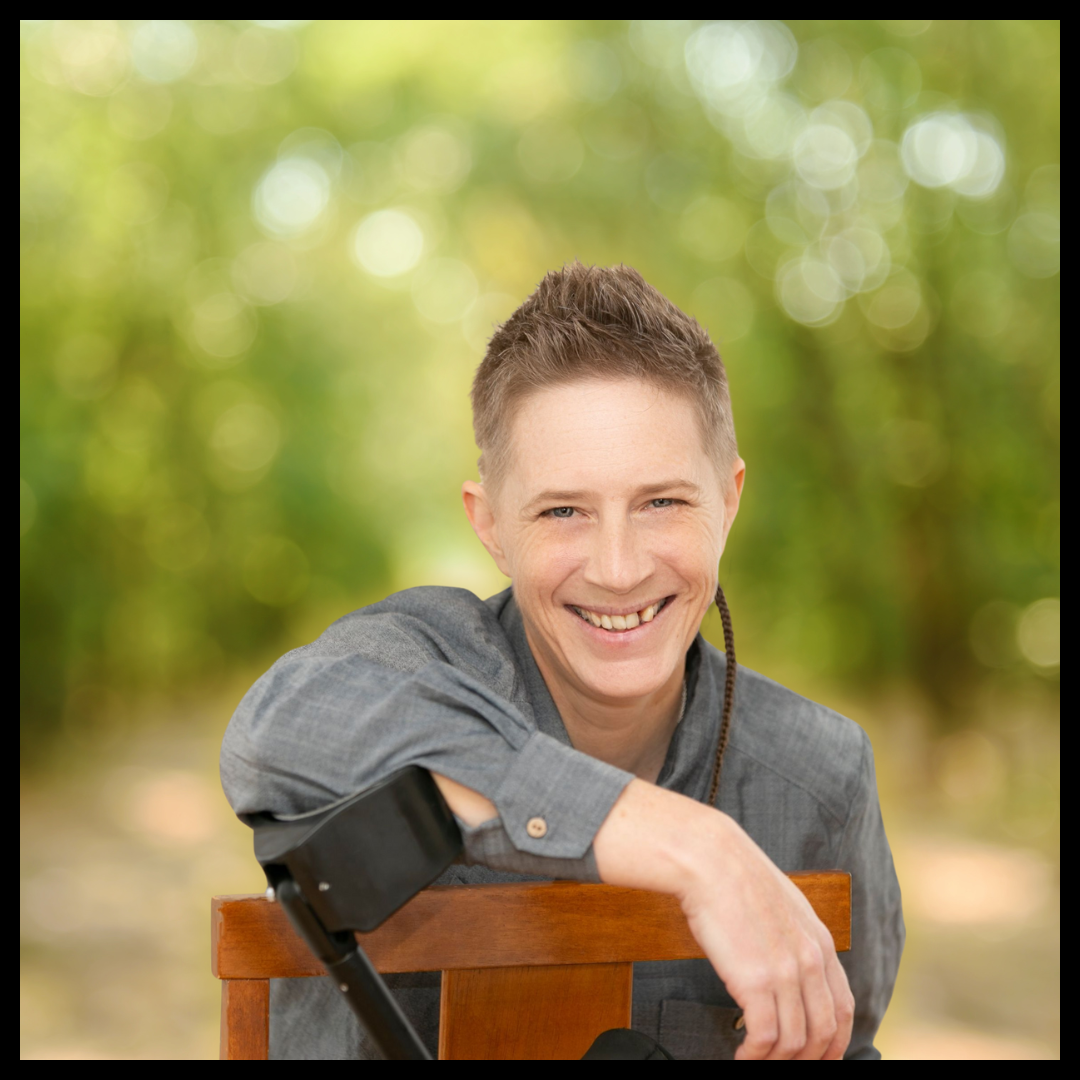 A person with short hair, wearing a light blue/grey shirt, smiling.