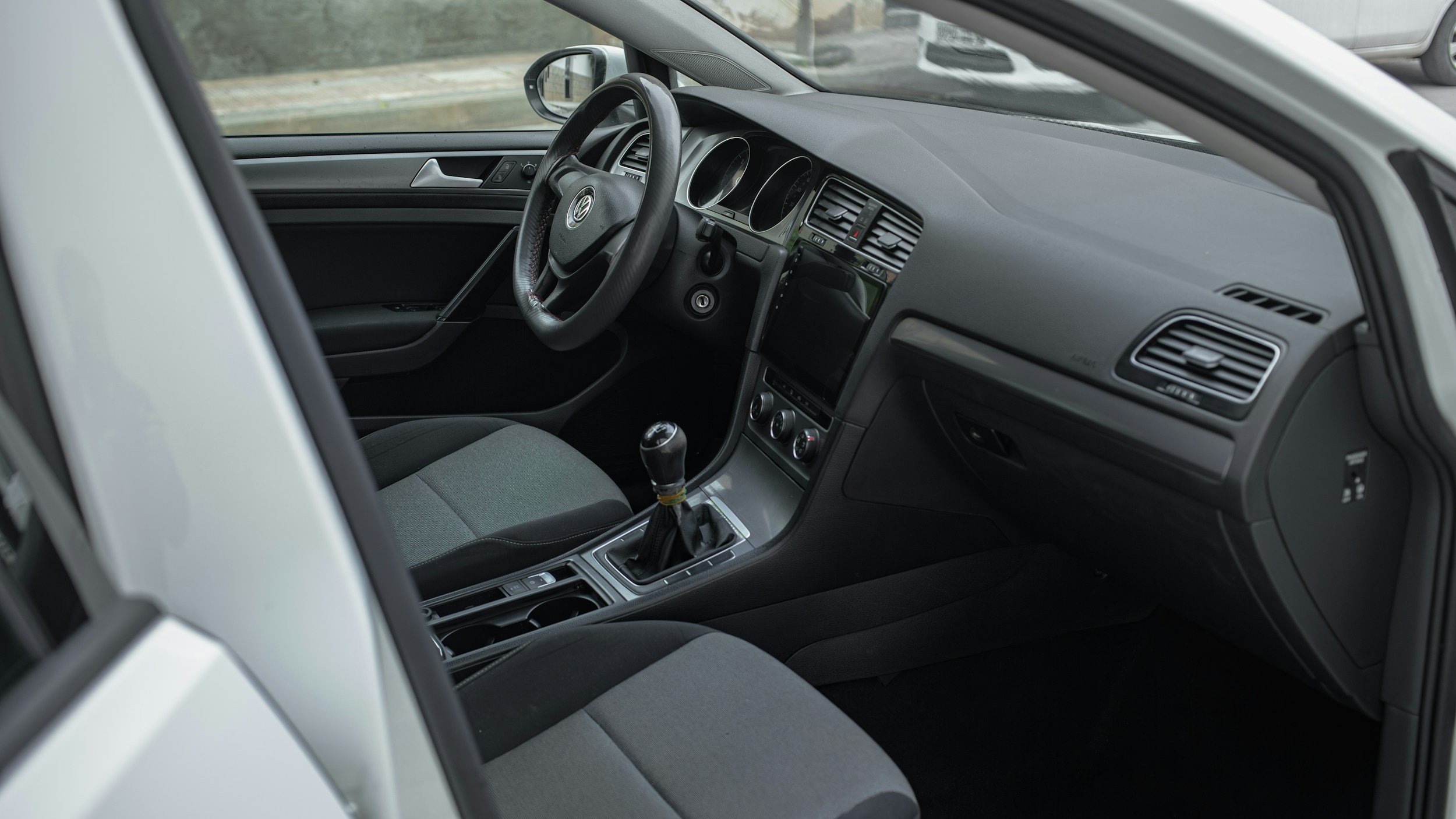 Interior of a Volkswagen car with manual transmission, black dashboard, and gray fabric seats.