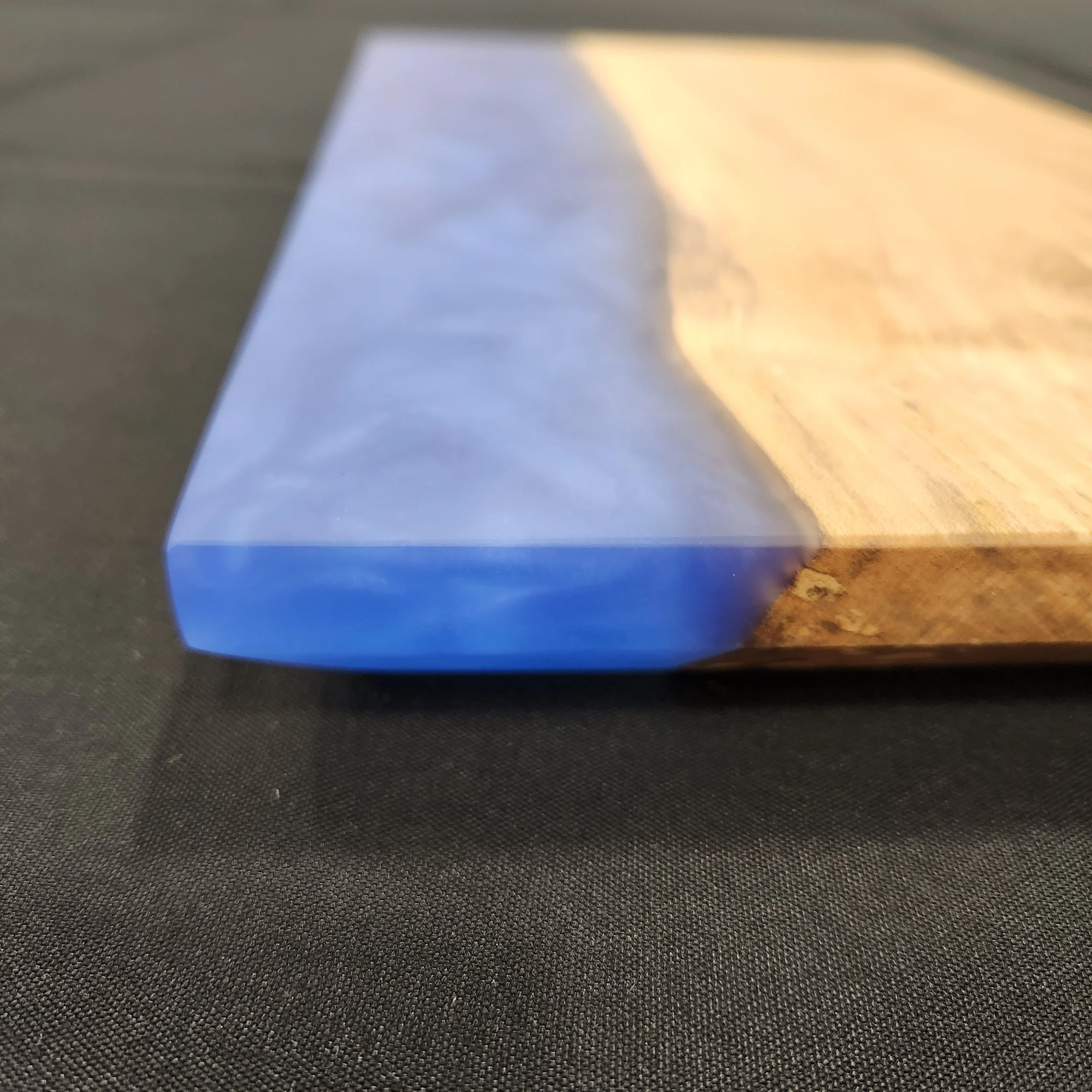 Close up of edge of 16 x 9 Maple Wood Epoxy Charcuterie Board with Deep Blue Sea epoxy