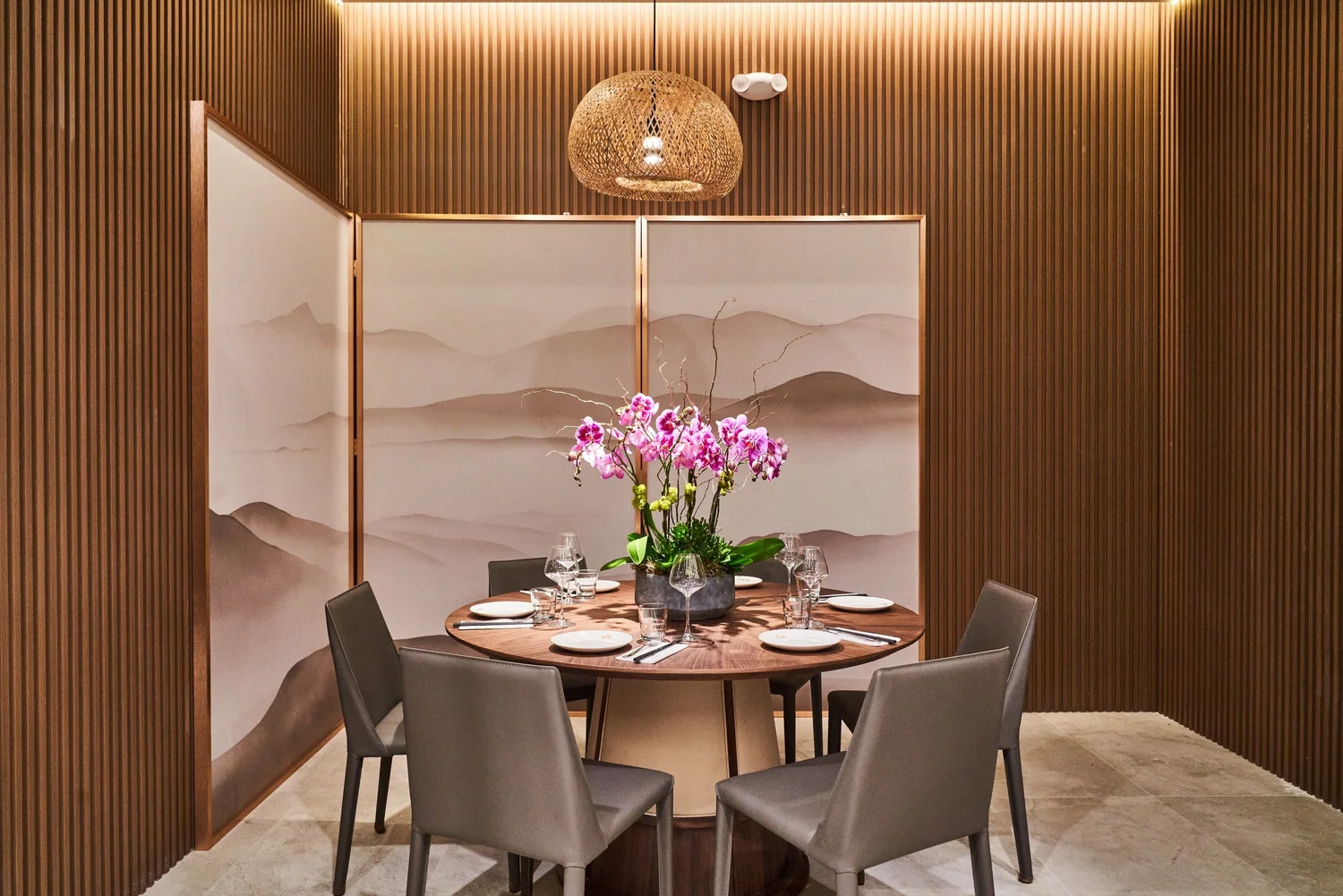 The private room at Le Soleil Stonestown — a round table set for six with orchids, a painted screen and warm wood walls