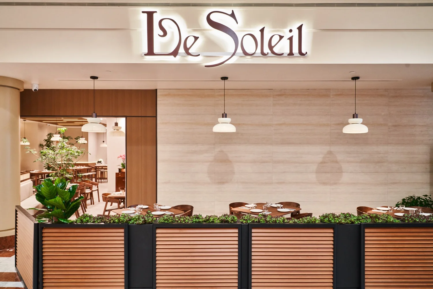 The patio at Le Soleil Stonestown — tables behind a slatted planter wall under the Le Soleil sign