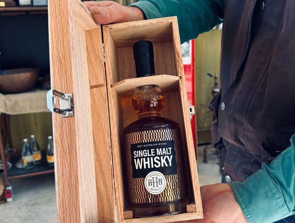 Person holding a wooden box containing a bottle of HHH Spirits Western Australian single malt whiskey.