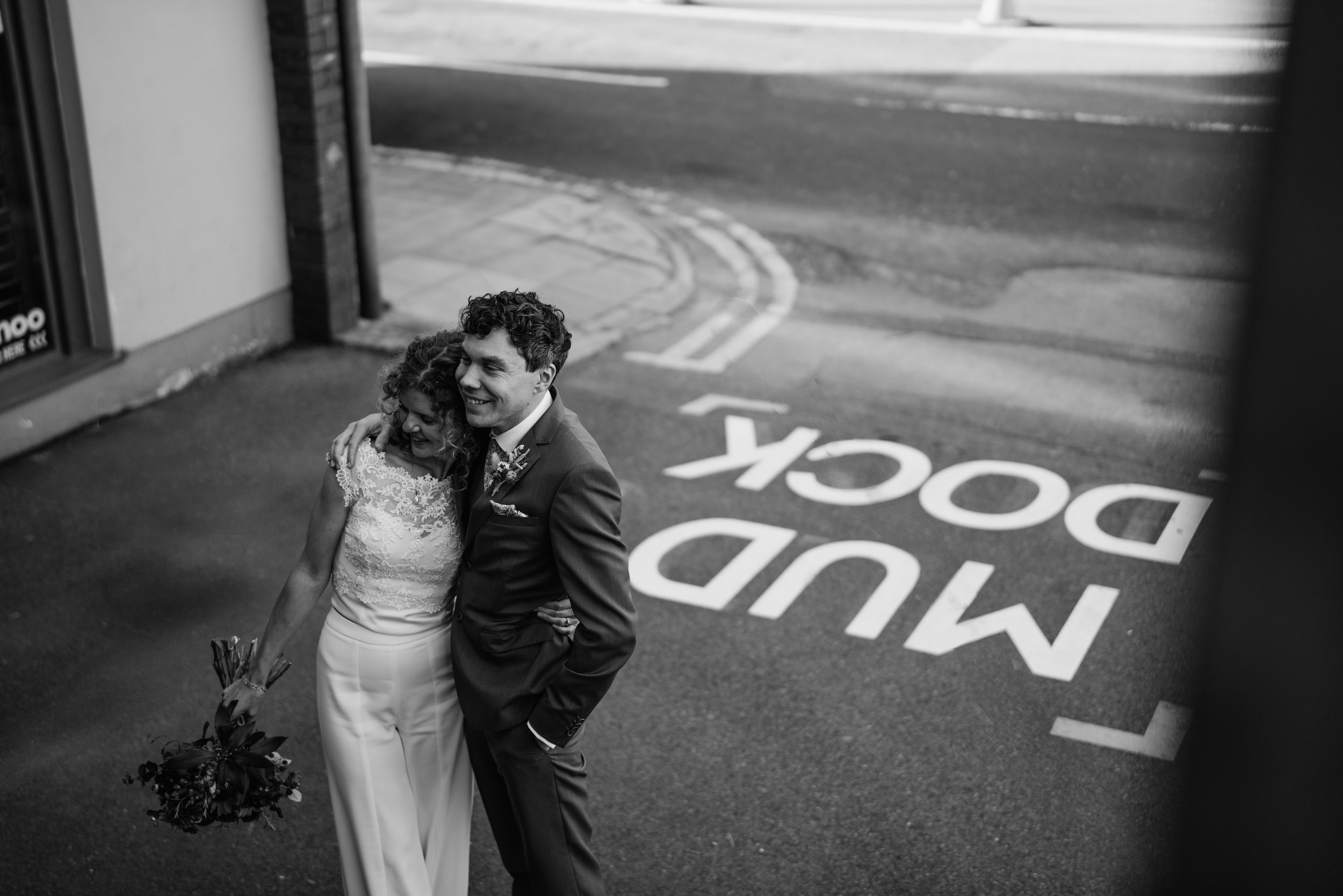 candid photo of bride and groom in front of mud dock sign