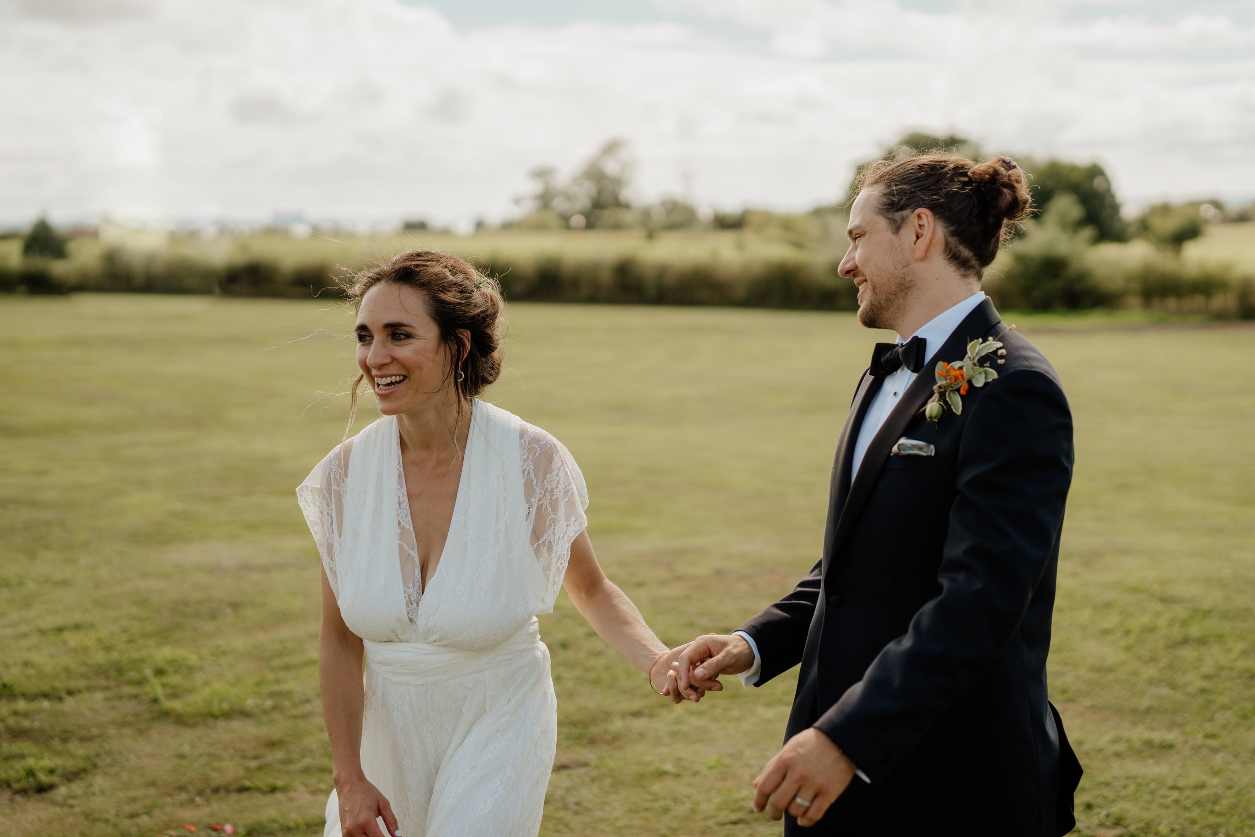 candid photo of bride and groom walking in field