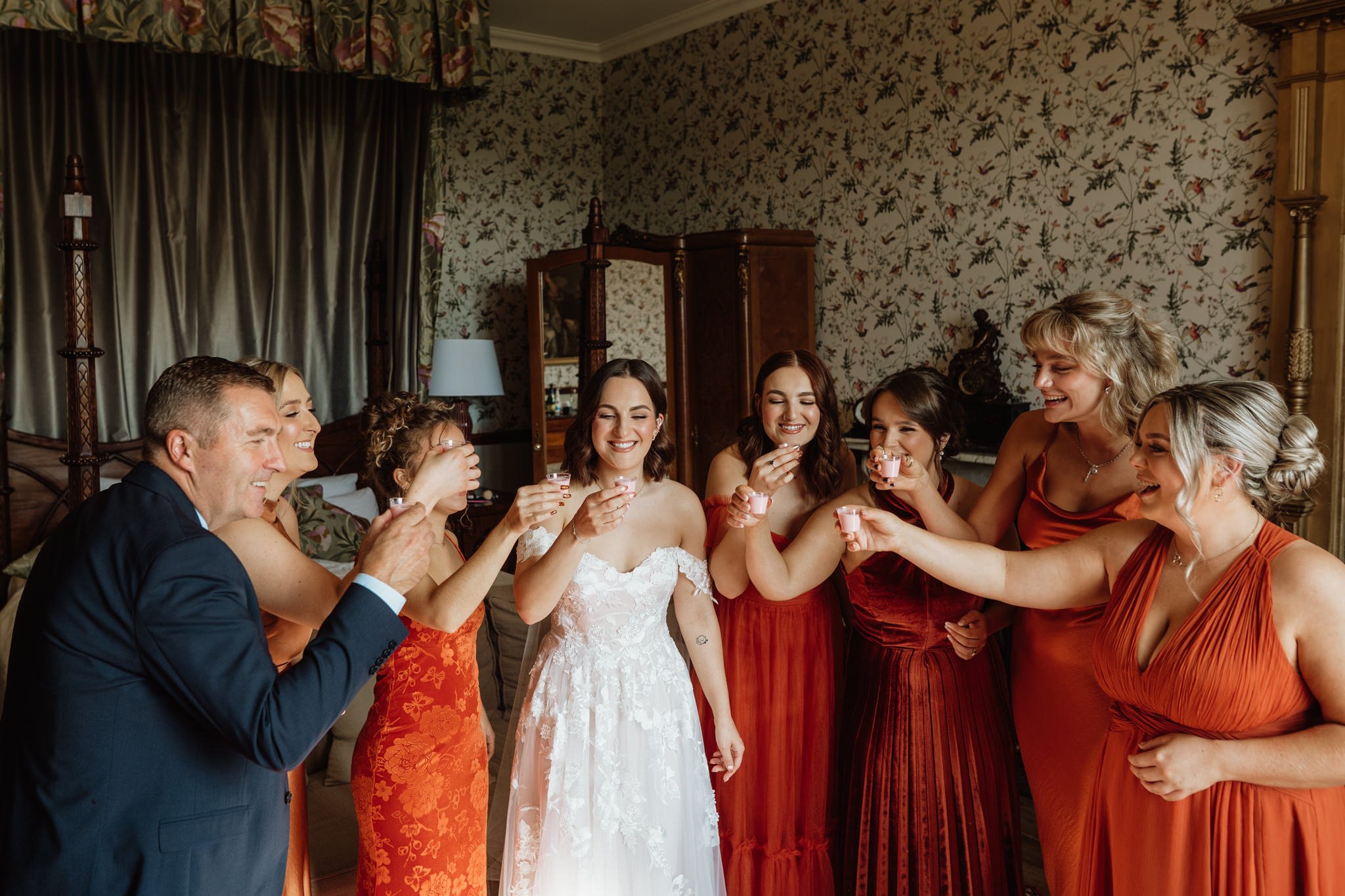 bride and bridesmaids do a shot of tequila in a bedroom