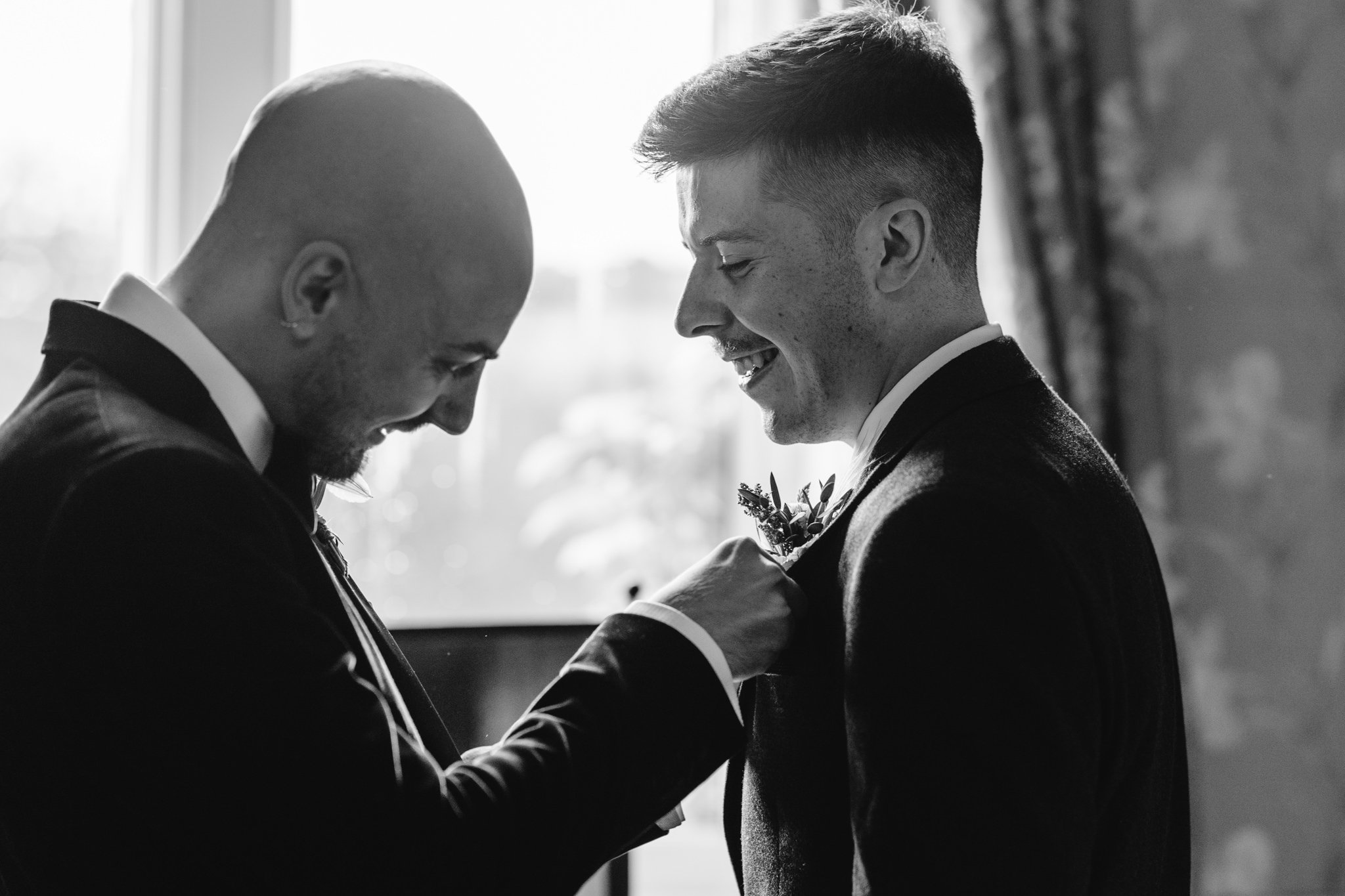 groom putting on groomsman buttonhole