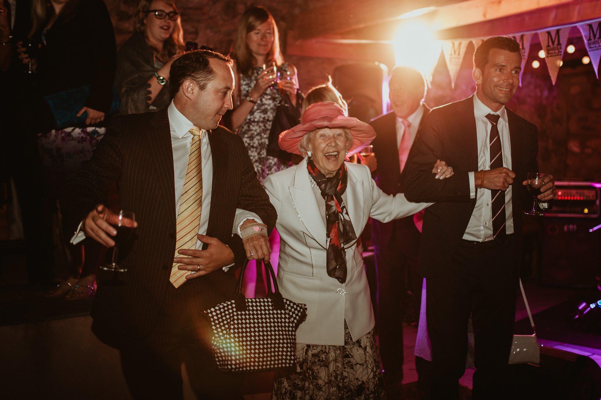photo of two mean leading grandma on to the dancefloor