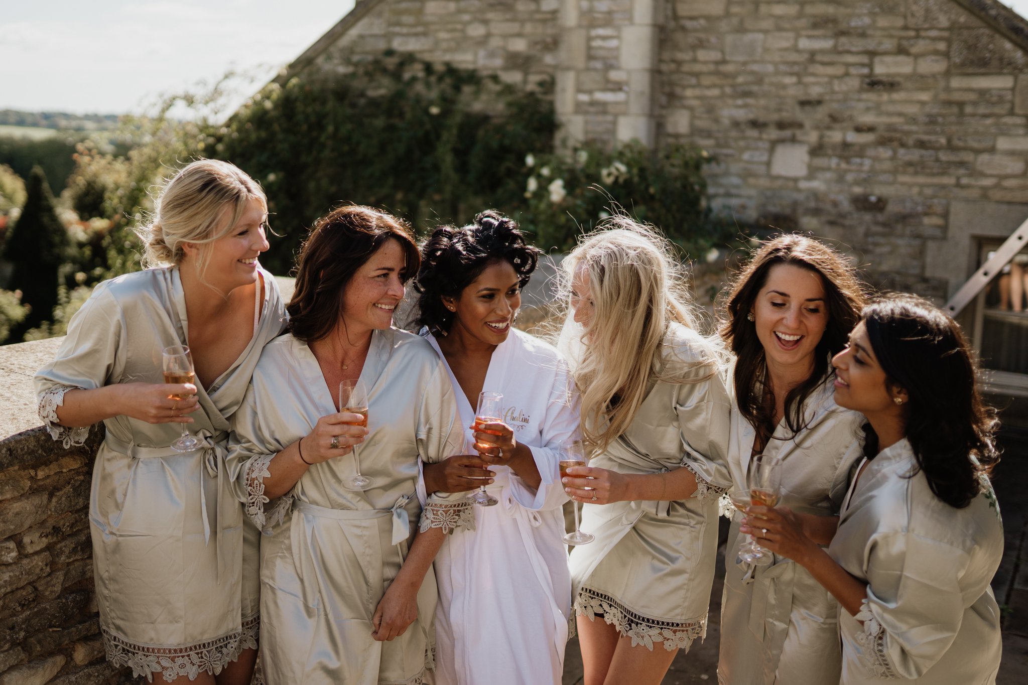 bride and bridesmaids in matching robes laughing on the balcony at euridge