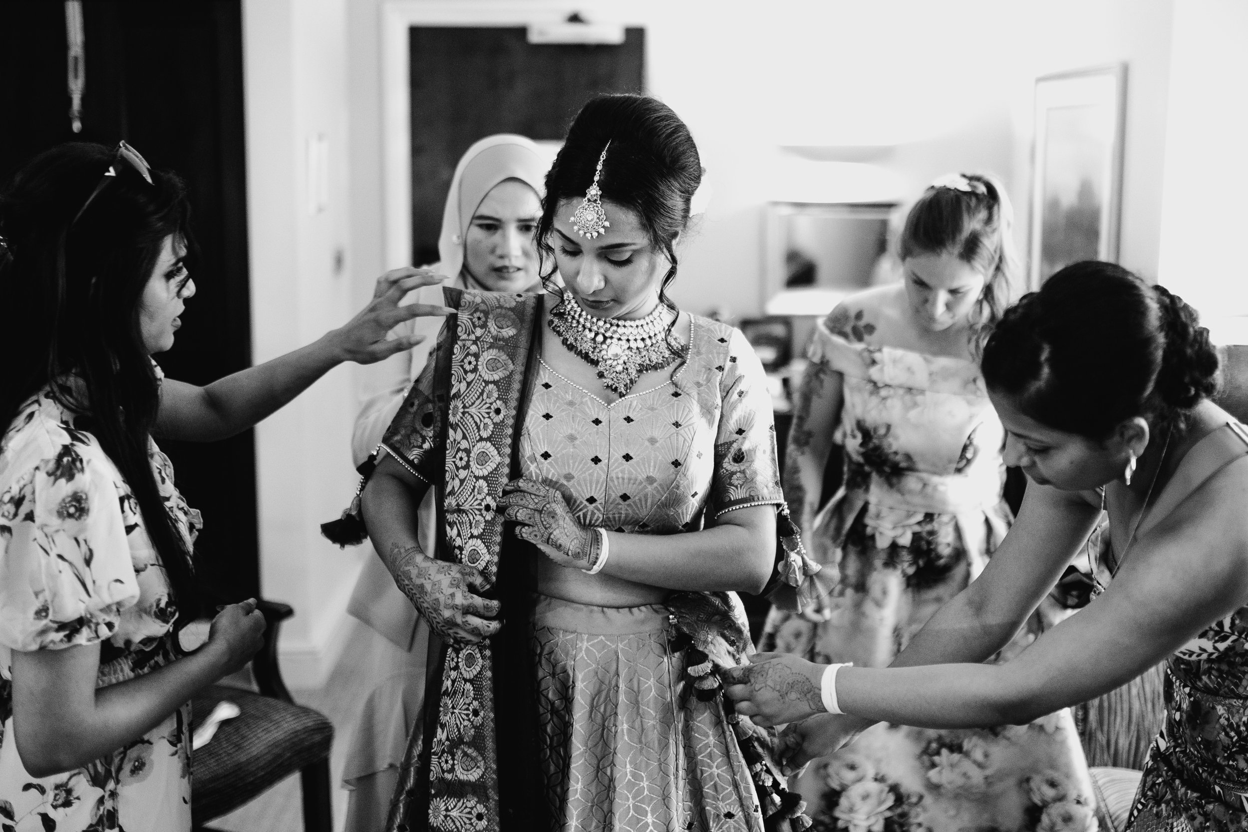 Indian bride getting ready with family adjusting her outfit