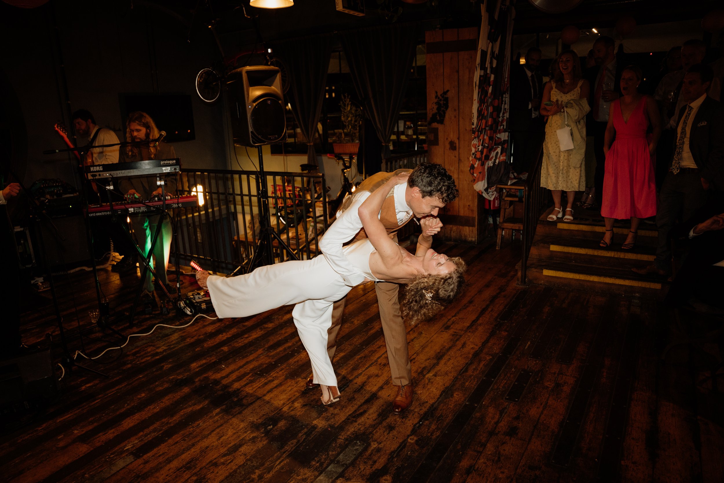 bride wearing jumpsuit and groom dip during their first dance