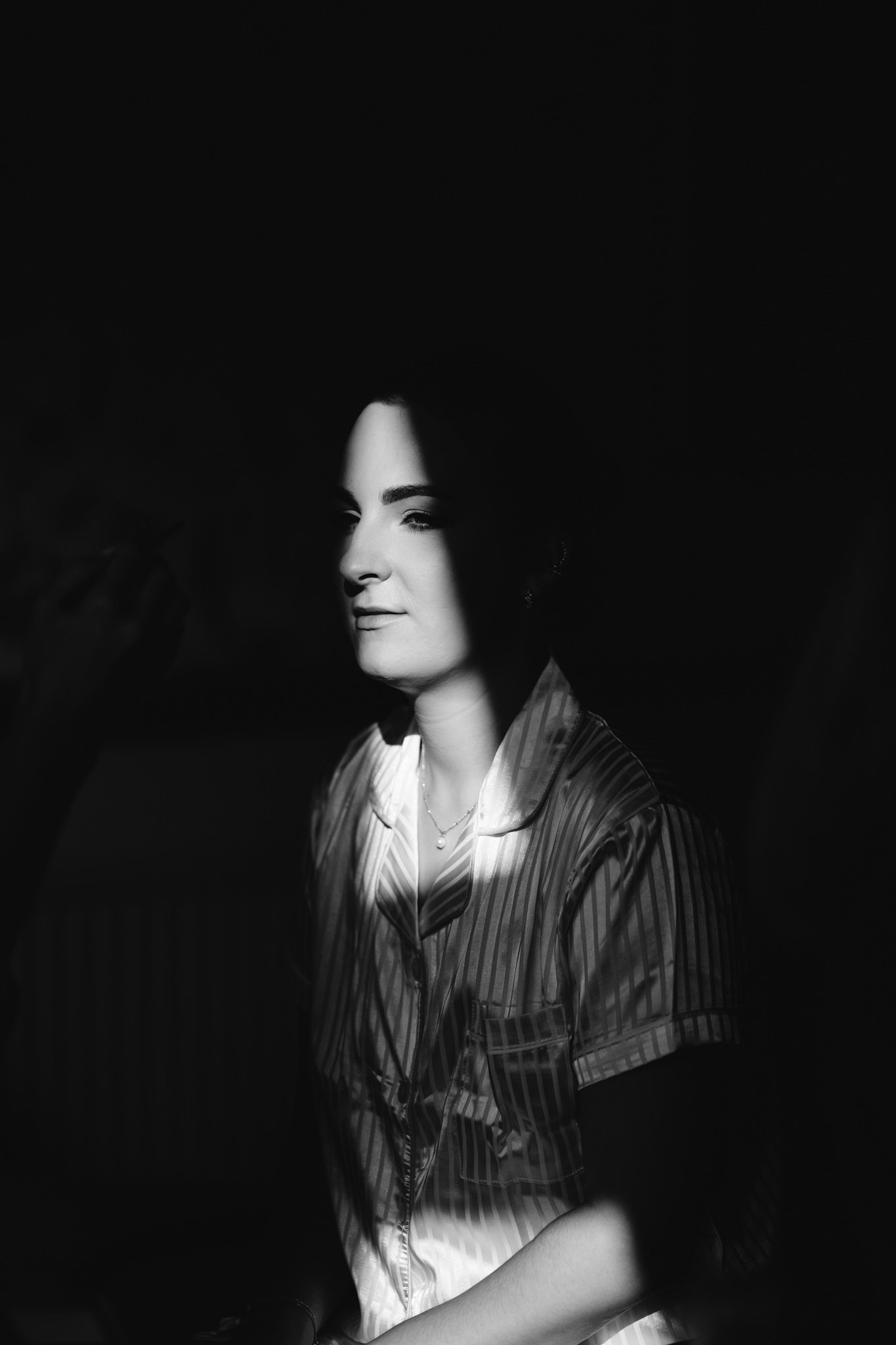 bride lit by sliver of light dramatic in black and white