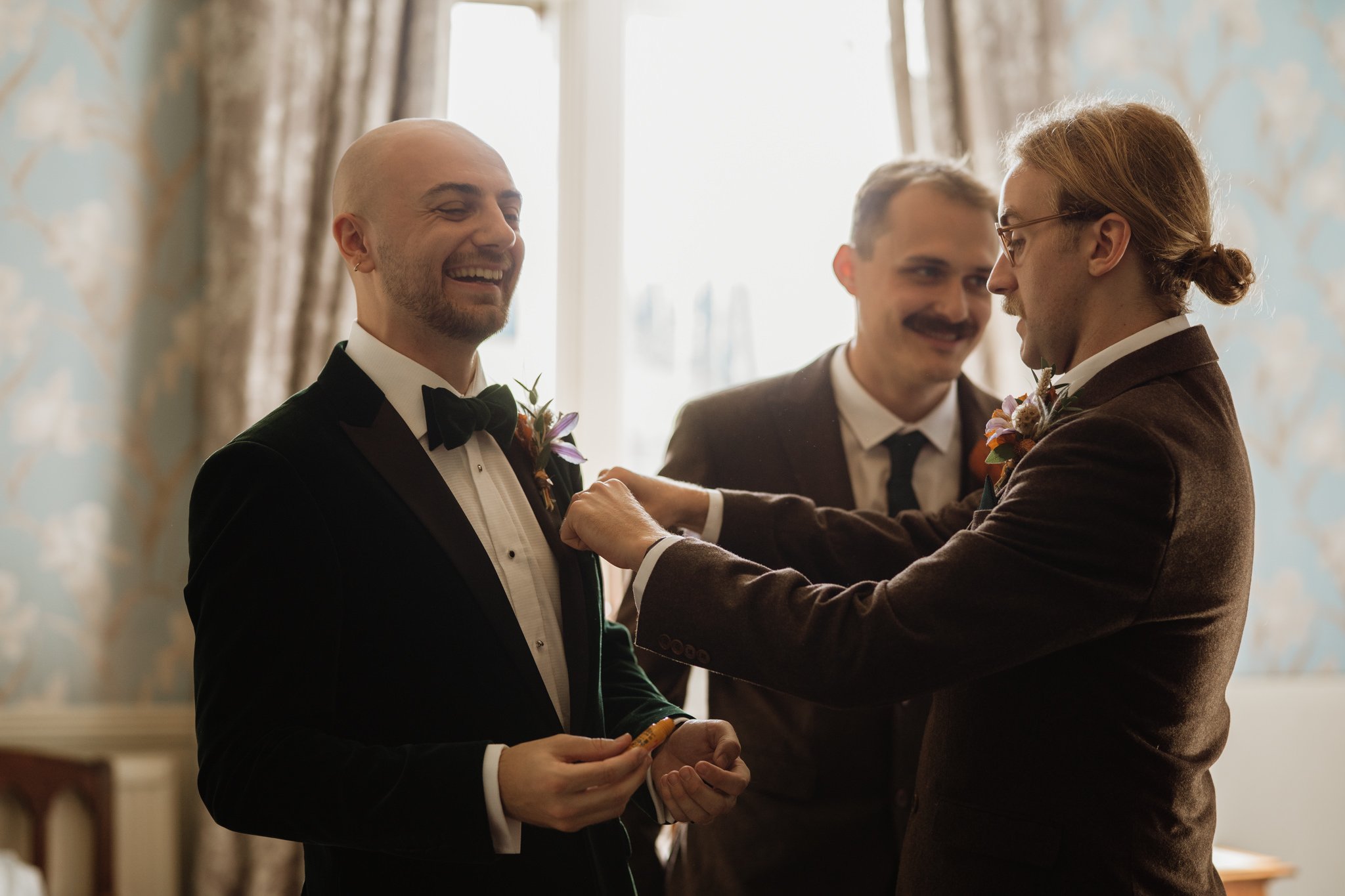 groomsmen helping groom with buttonhole