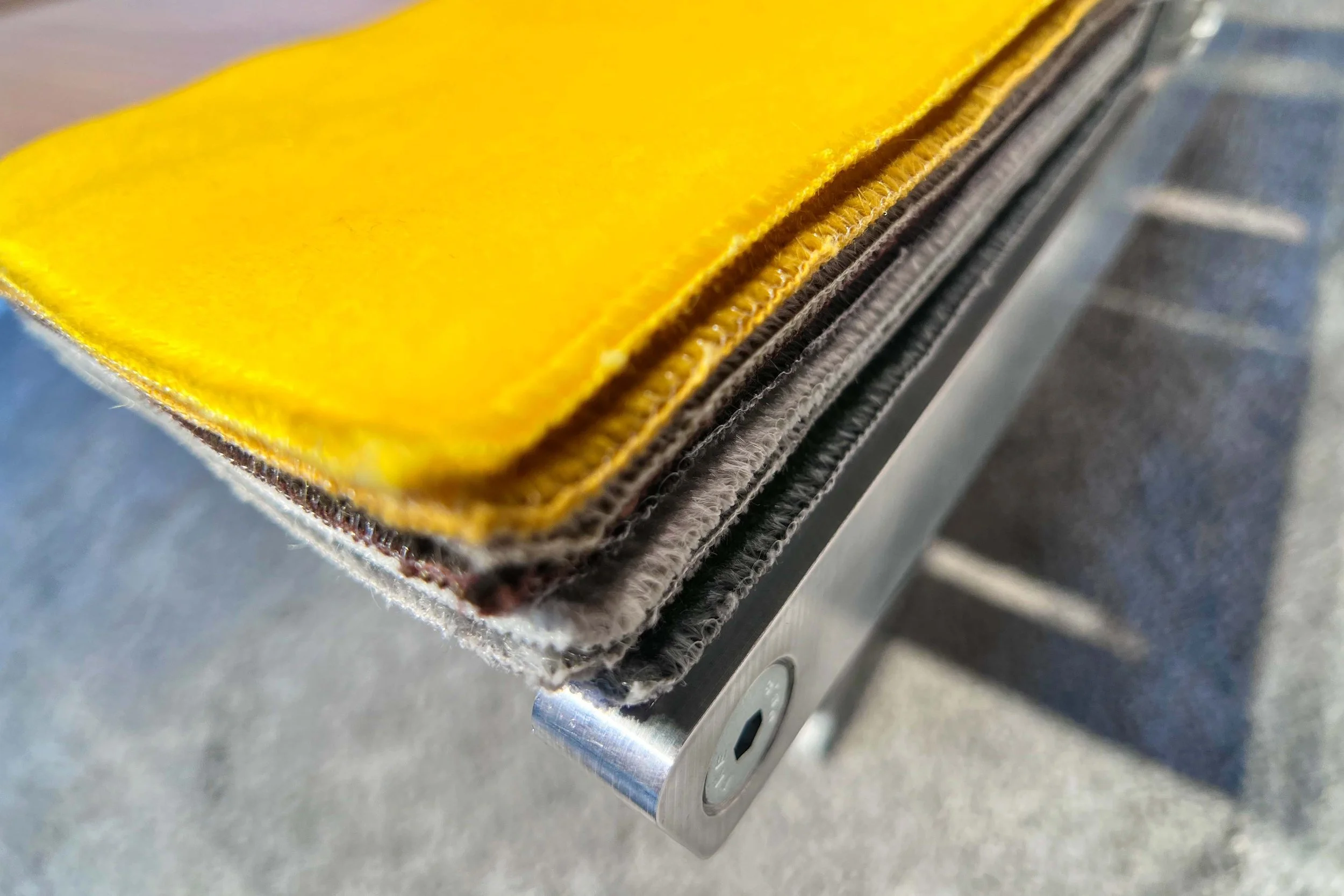 Close-up of a stack of fabric color swatches in yellow, brown, and gray, placed on a metal surface.