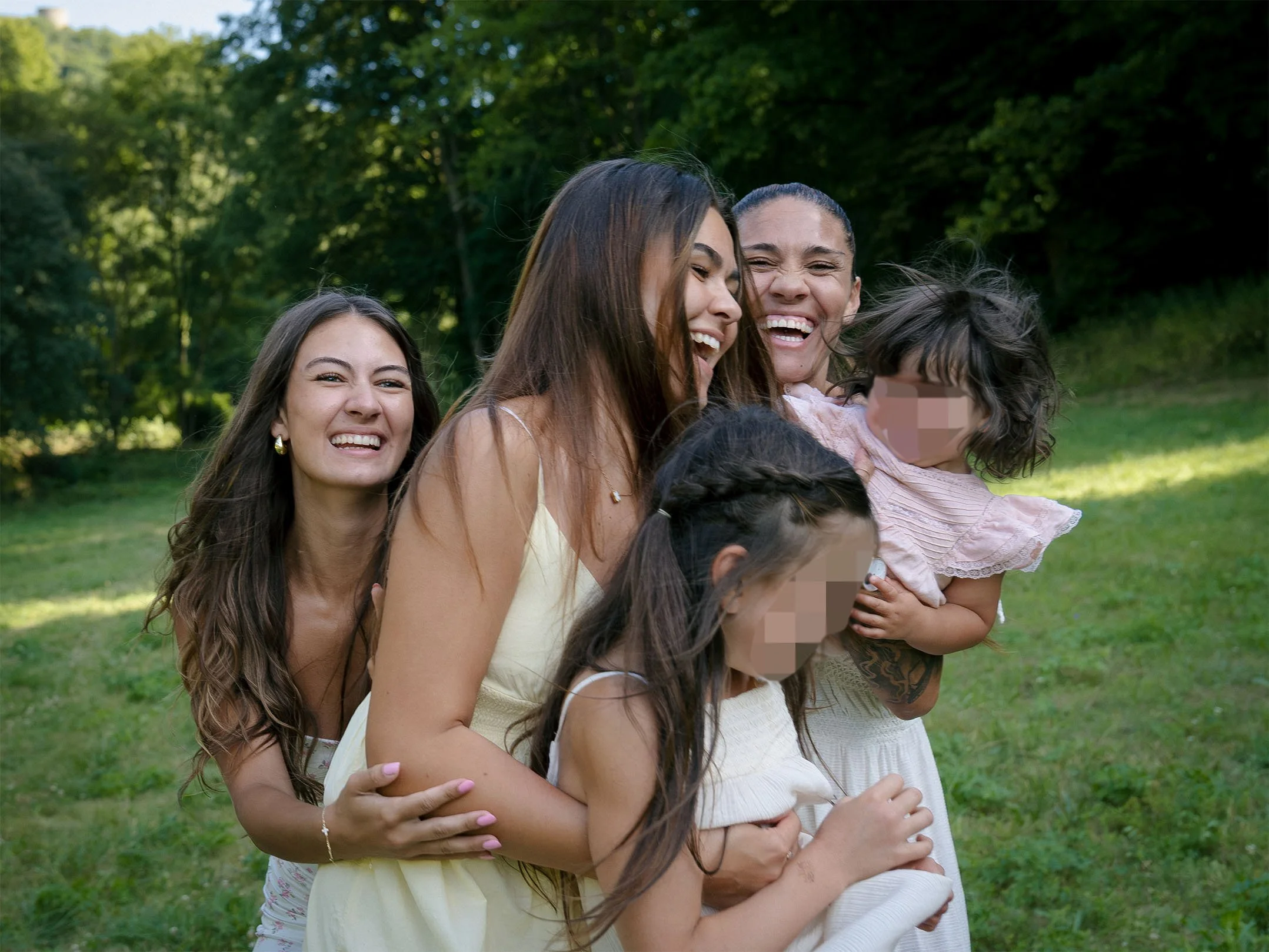 Fünf lachende Frauen und ein lachendes Mädchen, die miteinander umarmen, im Freien, umgeben von Bäumen. Entstanden bei einem Familien Shooting in Schmitten im Taunus.