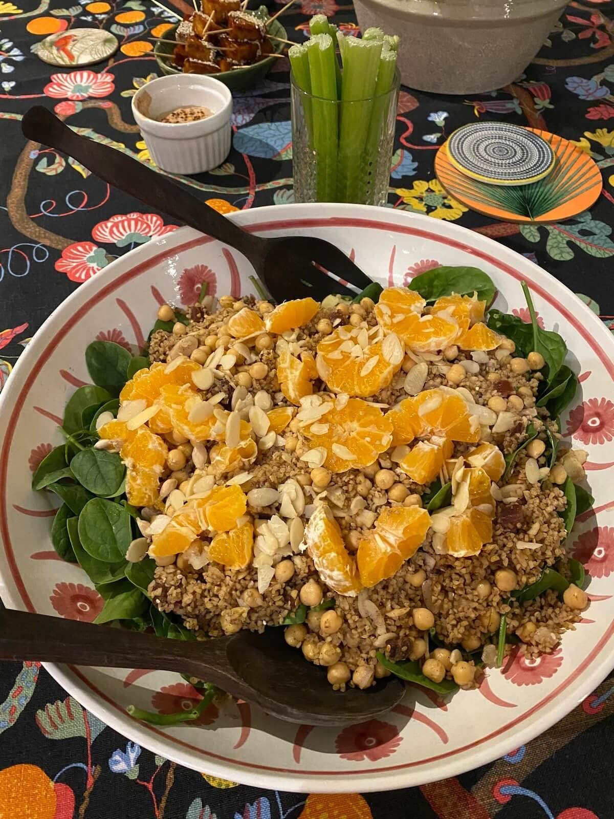 chickpea, spinach, orange and flaked almond salad in a bowl with a spoon