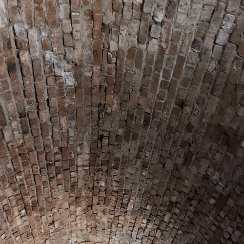 Close-up of a brick arched ceiling with aged and weathered bricks.