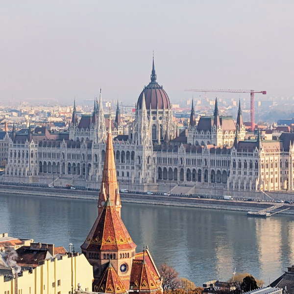 The Hungarian Parliament Building in Budapest seen from across the Danube River with an overcast sky.