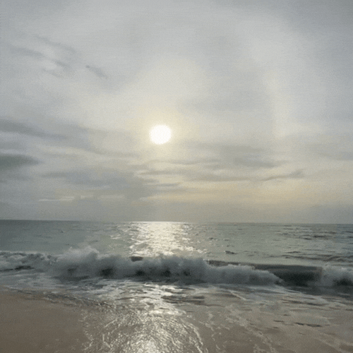 Sunset over the ocean with waves crashing on the shore