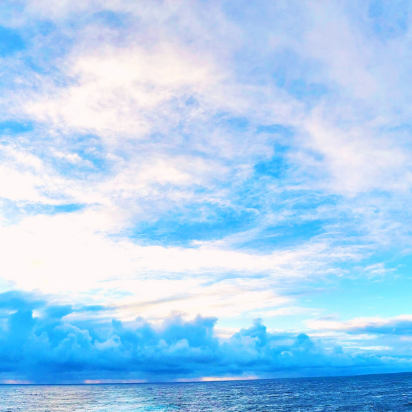 View of a cloudy sky over the ocean with blue and white clouds.