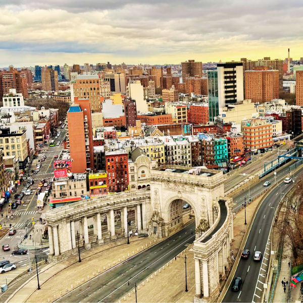 Aerial view of a cityscape with a historic triumphal arch and a busy street.
