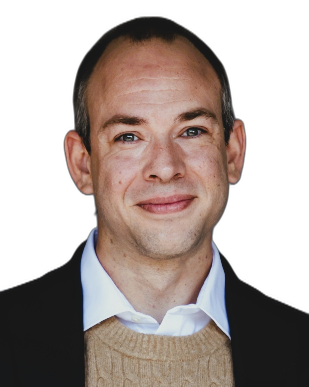 Portrait of a man with short dark hair, light skin, wearing a white collared shirt, beige sweater, and black blazer, against a black background.