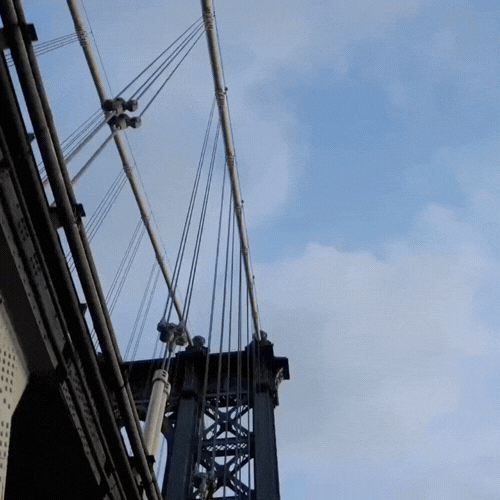 Close-up view of a suspension bridge's towers and cables against a blue sky.
